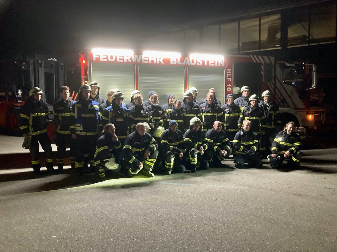 Bild einer Feuerwehrteams vor einem Einsatzwagen bei Nacht