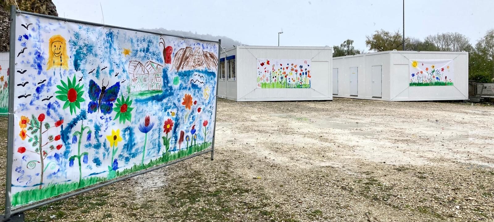 Außenansicht von Containerwohnungen zur Unterbringung Geflüchteter, mit von Kindern gestalteten Plakaten verschönert