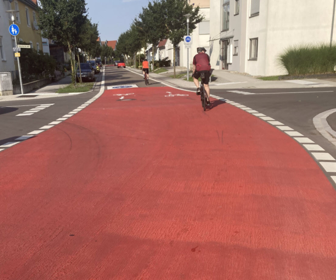 Eine Straßenkreuzung mit deutlicher roter Markierung des Radwegs.