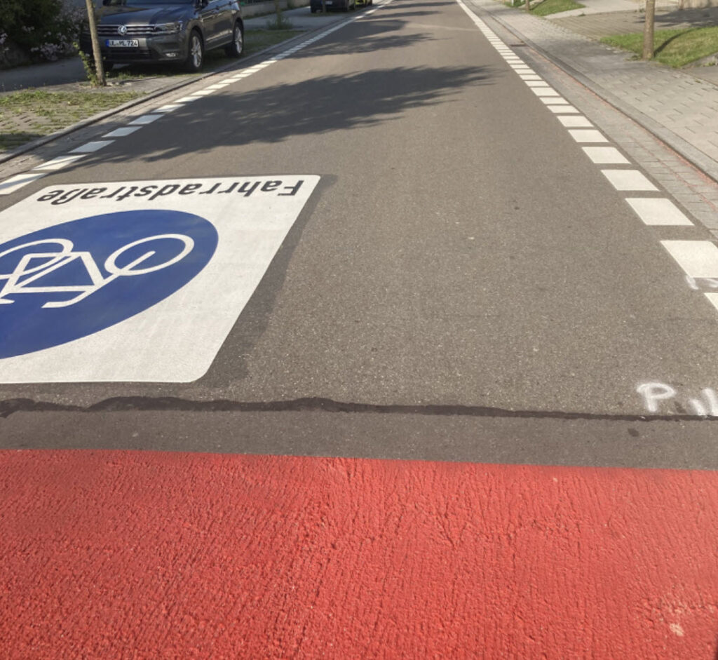 Eine Straße mit großer aufgemalter Kennzeichnung "Fahrradstraße" und einem rot markierten Kreuzungsanteil